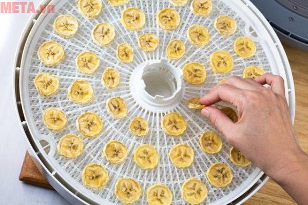 Dải đều các lát chuối lên khay máy sấy hoa quả