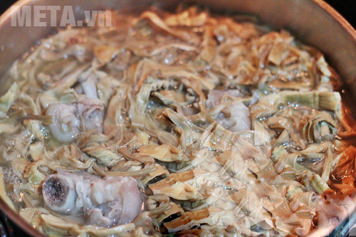 Cho măng vào nồi xương đang ninh và đun chín măng Cho măng vào nồi xương đang ninh và đun chín măng