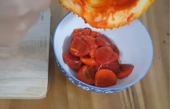 Trút ruột gấc ra bát rồi trộn với 1 thìa rượu trắng và 1 chút muối Trút ruột gấc ra bát rồi trộn với 1 thìa rượu trắng và 1 chút muối