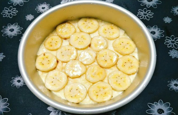 Xếp chuối vào nồi cơm điện rồi đổ hỗn hợp bột vào nồi cơm điện