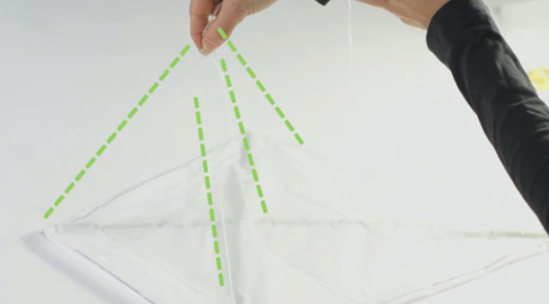 Dùng kéo chọc thủng một lỗ nhỏ ngay bên trên nơi hai cây que giao nhau