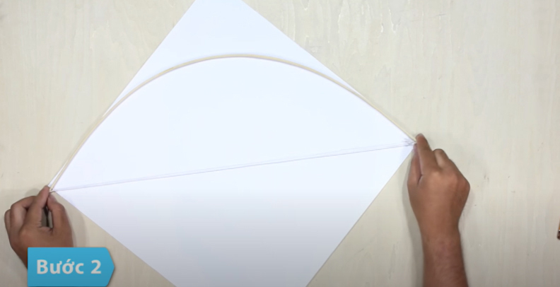 Dùng hồ và các băng giấy dán chúng lại để cố định cánh cung vào diều, sao cho dây cước chạy theo 1 đường chéo của diều