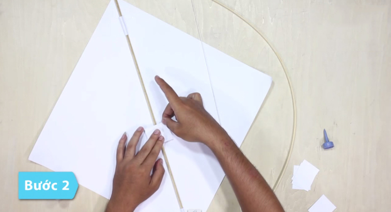 Lấy thanh tre còn lại dán vuông gốc với cánh cung, chạy dọc theo đường chiếu còn lại của diều