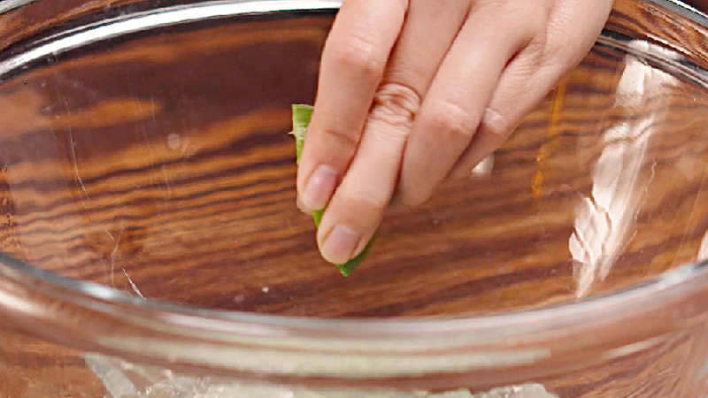 Cho 1/2 quả chanh và 1/2 thìa cà phê muối vào bát nha đam, dùng tay trộn đều nhẹ nhàng rồi từ từ đổ nước vào ngâm khoảng 15 phút. Cho 1/2 quả chanh và 1/2 thìa cà phê muối vào bát nha đam, dùng tay trộn đều nhẹ nhàng rồi từ từ đổ nước vào ngâm khoảng 15 phút.