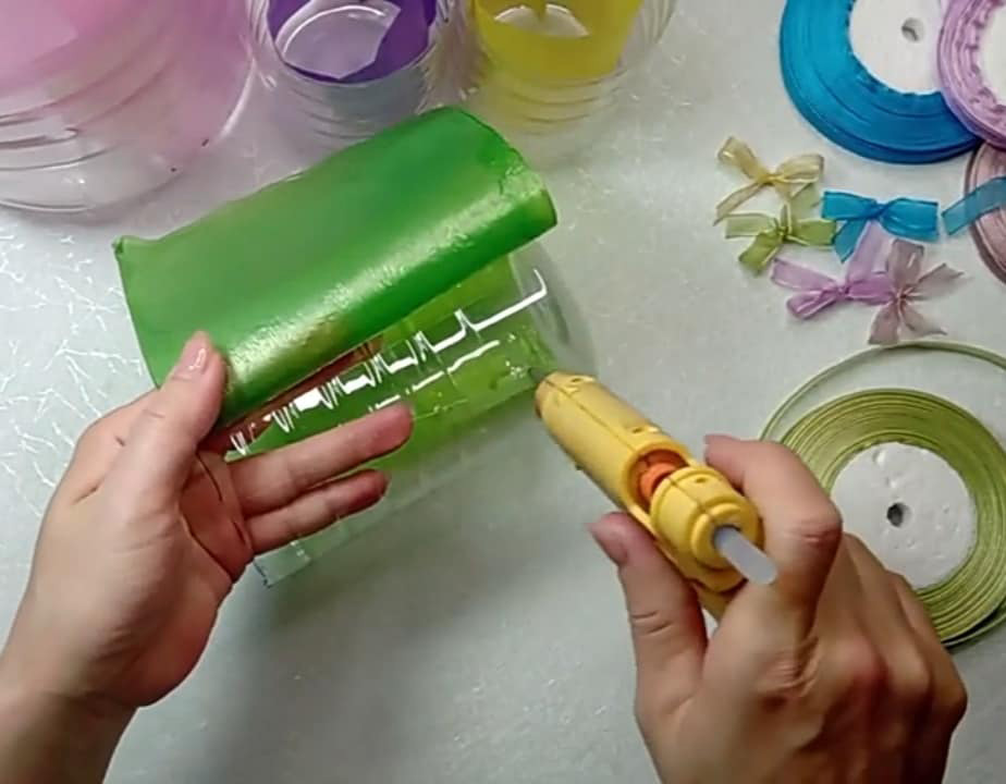 Đo kích thước chai nhựa để cắt túi nylon cho phù hợp rồi dùng súng bắn keo nến dán túi xung quanh vỏ chai