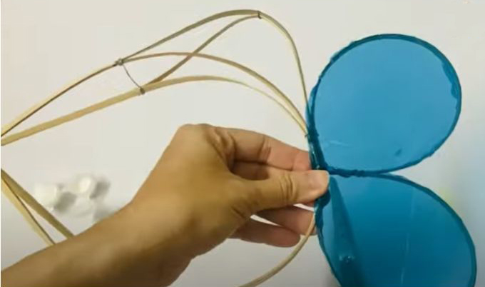 Khi đã có giấy kính, bạn dùng keo dán gắn chúng vào khung tre hình con cá