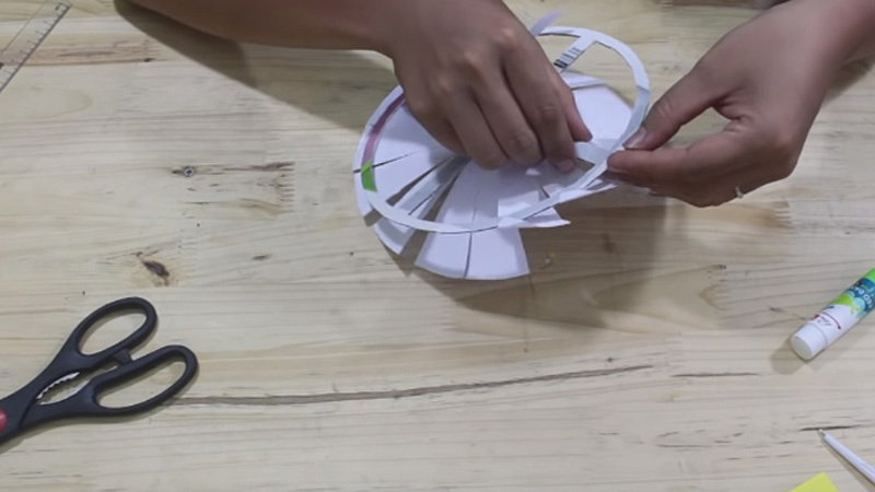 Tiếp theo, bạn dán một phần nhỏ đoạn vừa gập 0,5cm vào thanh của hình tròn