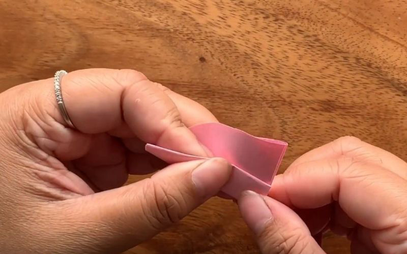 Từ phần góc nhọn của tờ giấy hình tròn, bạn gấp một đường nhỏ