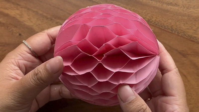 Bạn dán keo nối hai đầu giấy lại với nhau, chờ keo khô hẳn, bạn bung giấy ra là đã sẽ tạo được hình dáng của quả tròn trông giống quả châu