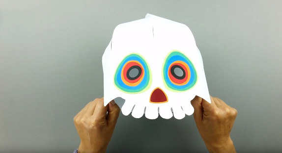 Cắt giấy màu khác để làm mắt và mũi cho chiếc mặt nạ rồi dán cố định bằng keo dán